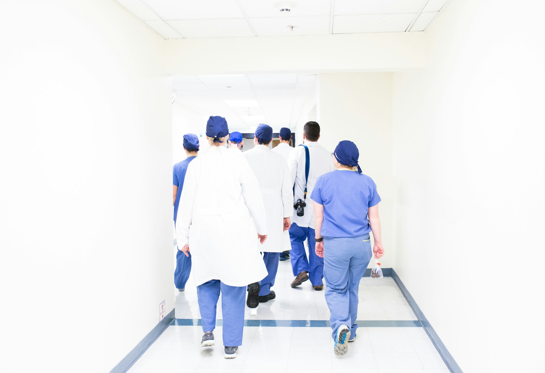 Equipe de profissionais de saúde caminhando em corredor hospitalar